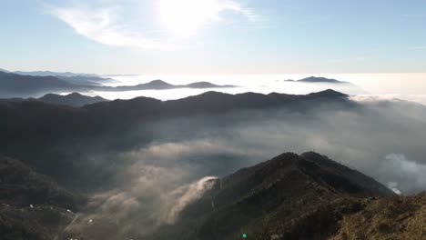 misty mountain peaks emerging above clouds during sunrise in genoa, liguria