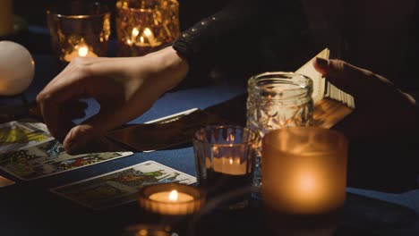 close up of woman giving tarot card reading on candlelit table holding the tower card