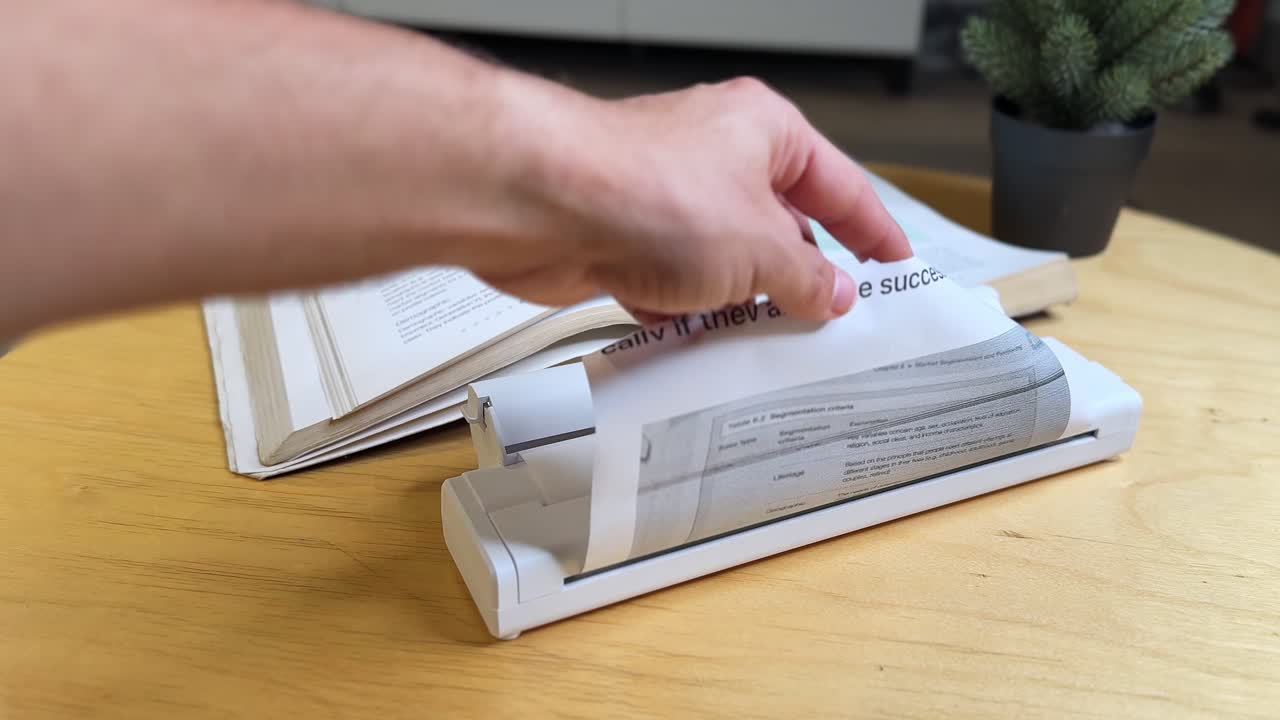 Closeup of hand scanning printed document with portable scanner on desk. Perfect for business, education, office, research, digital workflow, and productivity projects