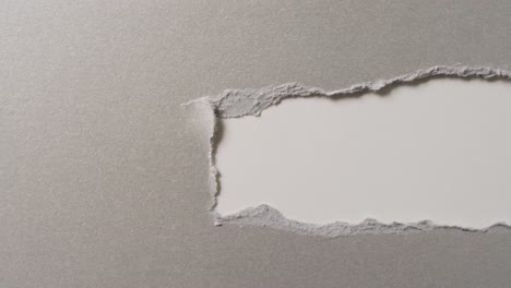 Video-of-close-up-of-torn-grey-paper-on-white-background