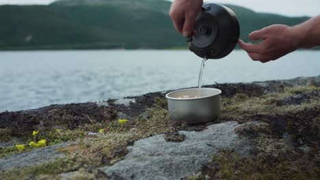 hands pouring warm water teapot into pot of multigrain rice outdoor