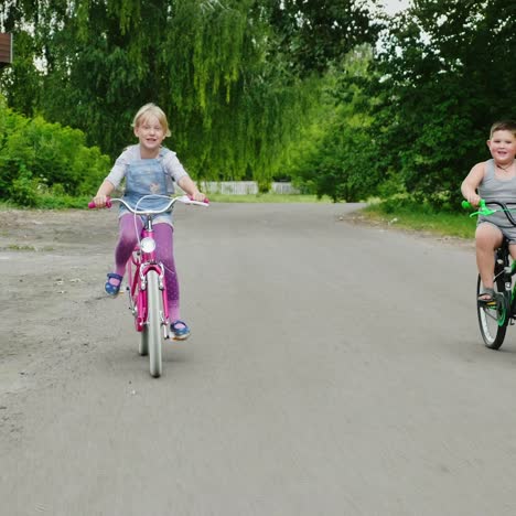 Two-Farm-Children-Are-Riding-Bicycles-In-The-Countryside