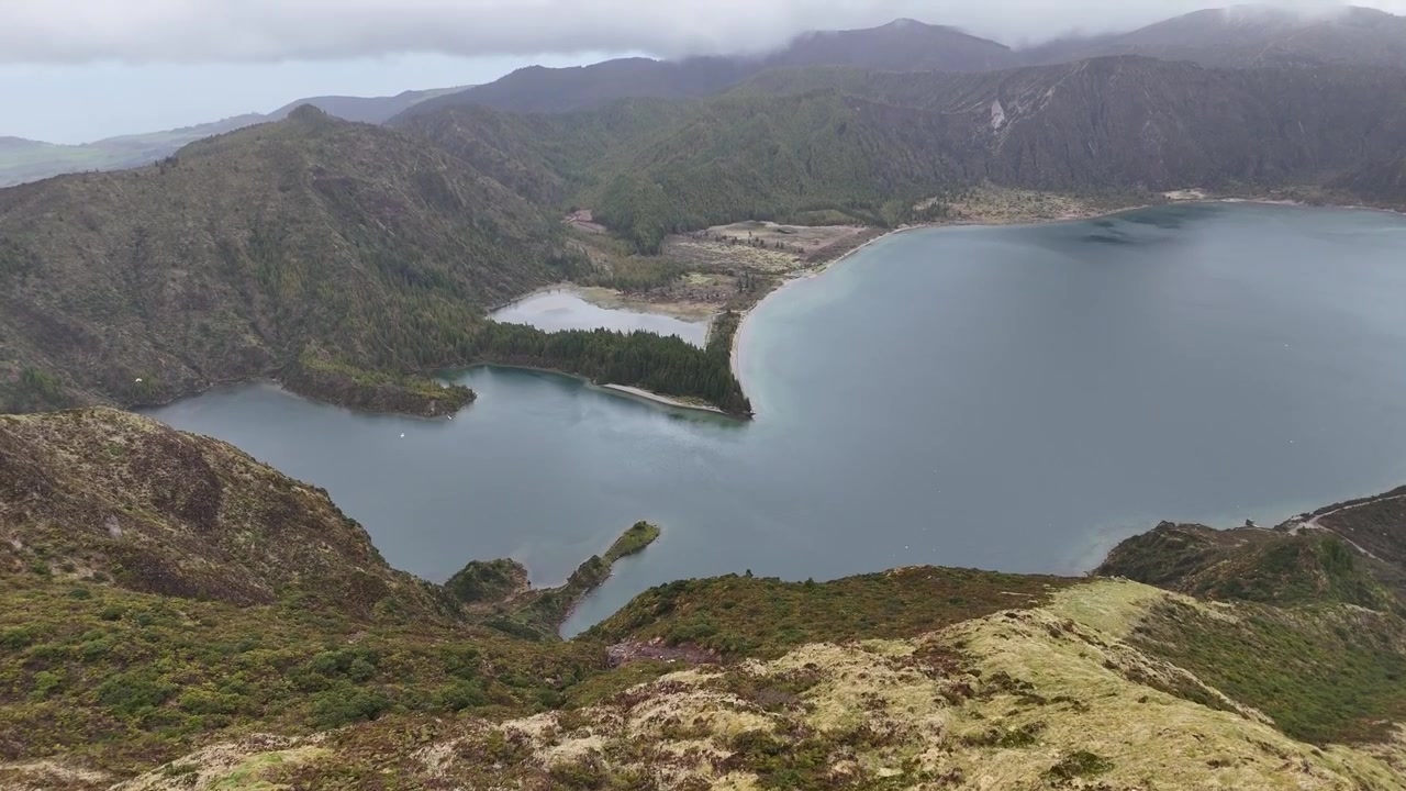 Azorlar'daki Lagoa do Fogo'nun yüksek dağ sırtları üzerinde hava drone uçuşu. Portekiz takımadalarının volkanik zirvelerinin ve yemyeşil yamaçlarının geniş görünümü.