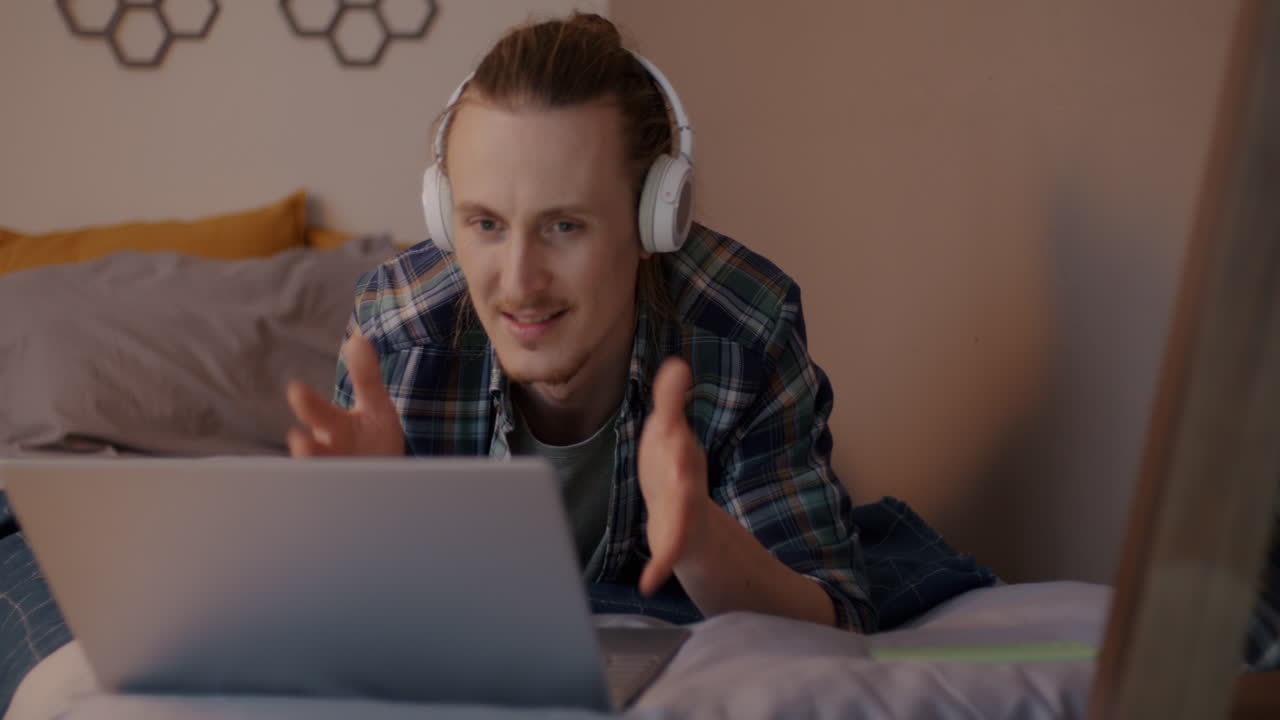 Man Video Chatting on Laptop in Bed