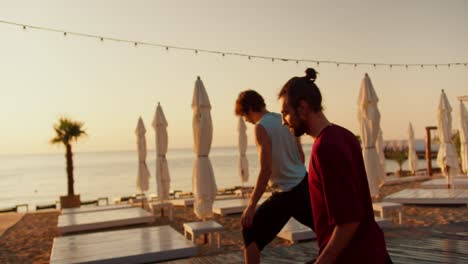 the two boys extended their arms to the sides and assumed a meditation position on the sunny beach in the morning. beautiful