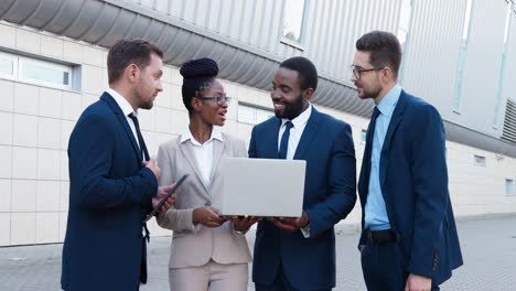 vista de cerca de un grupo de empresarios multiétnicos con ropa elegante hablando y usando dispositivos en la calle