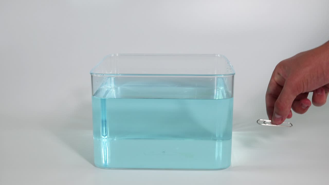 손으로 은 물 크에 종이 클립을 떨어뜨리는