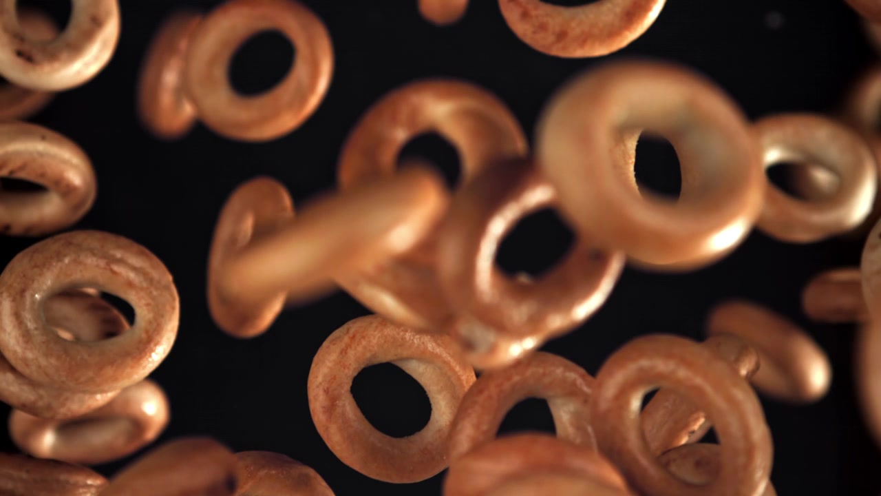 Bagel e pretzel dorati che cadono al rallentatore