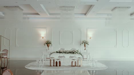 elegant white wedding altar with floral arrangements and lanterns in a minimalist venue