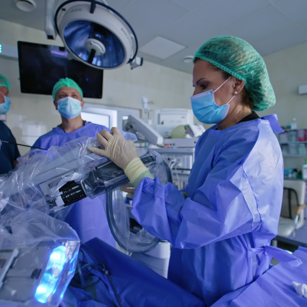 Female doctor disconnects the manipulator arm from the robotic arm. Specialist places a tool into special cup. Male doctors stand at backdrop
