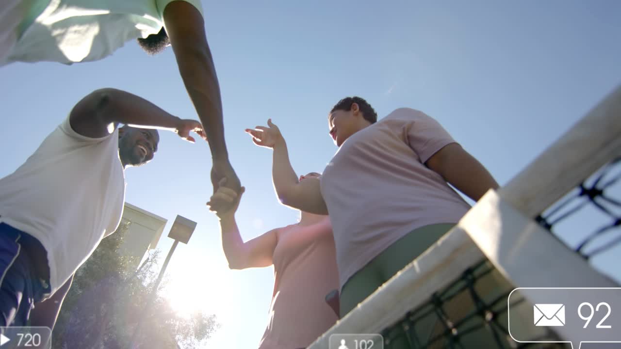 Four tennis players greeting at net shaking while racket player tapping phone floating social icons