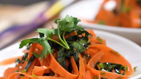picking up and serving orange pasta noodles colored or infused with tomato paste, carrots or chickpeas and garnished with fresh parsley sprig, closeup in restaurant or home kitchen on cutting board