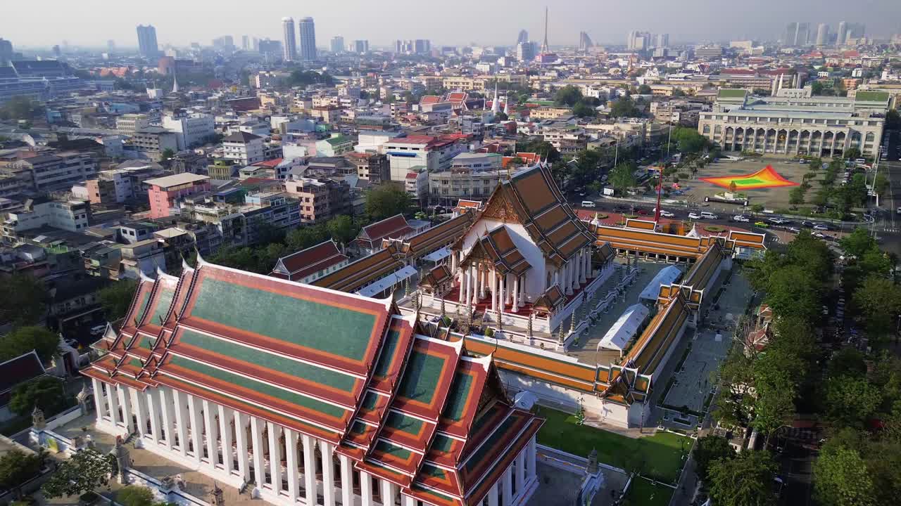 Aerial drone overview of Wat Suthat in Bangkok, Thailand, grand architecture in contrast to humble buildings