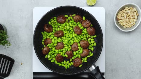 woman adding green beans to meatballs