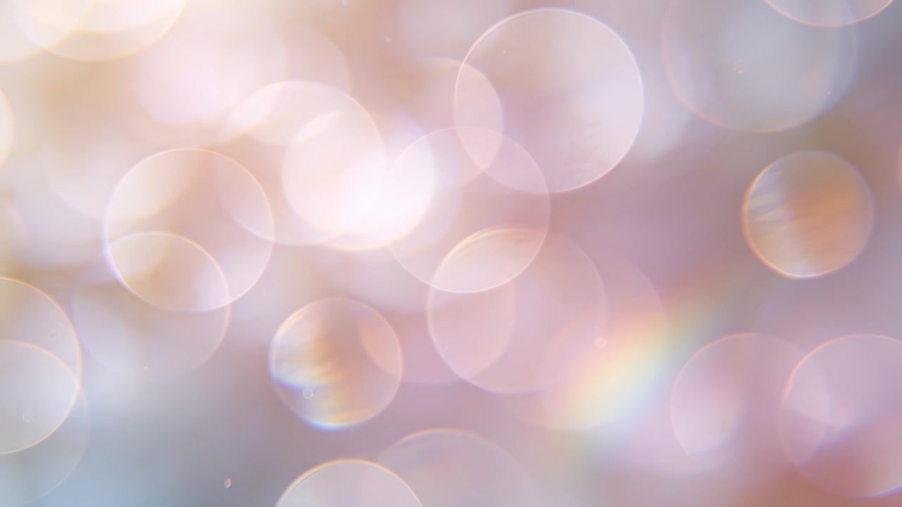Shifting light causing abstract bokeh cluster drifting in macro tabletop close-up, with prism band