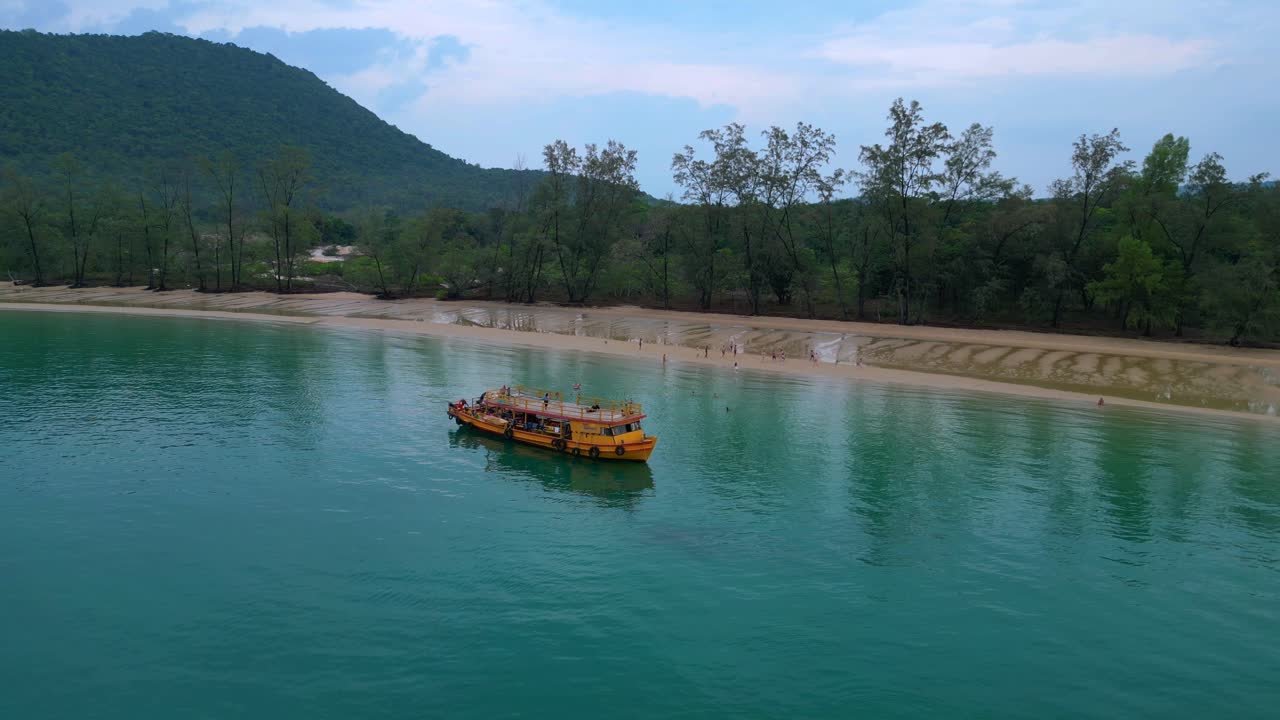 Tourists enjoying Koh Rong Sanloem beach and sea, swimming near a tour boat, aerial view from above. Nice aerial view flight static tripod hovering drone
