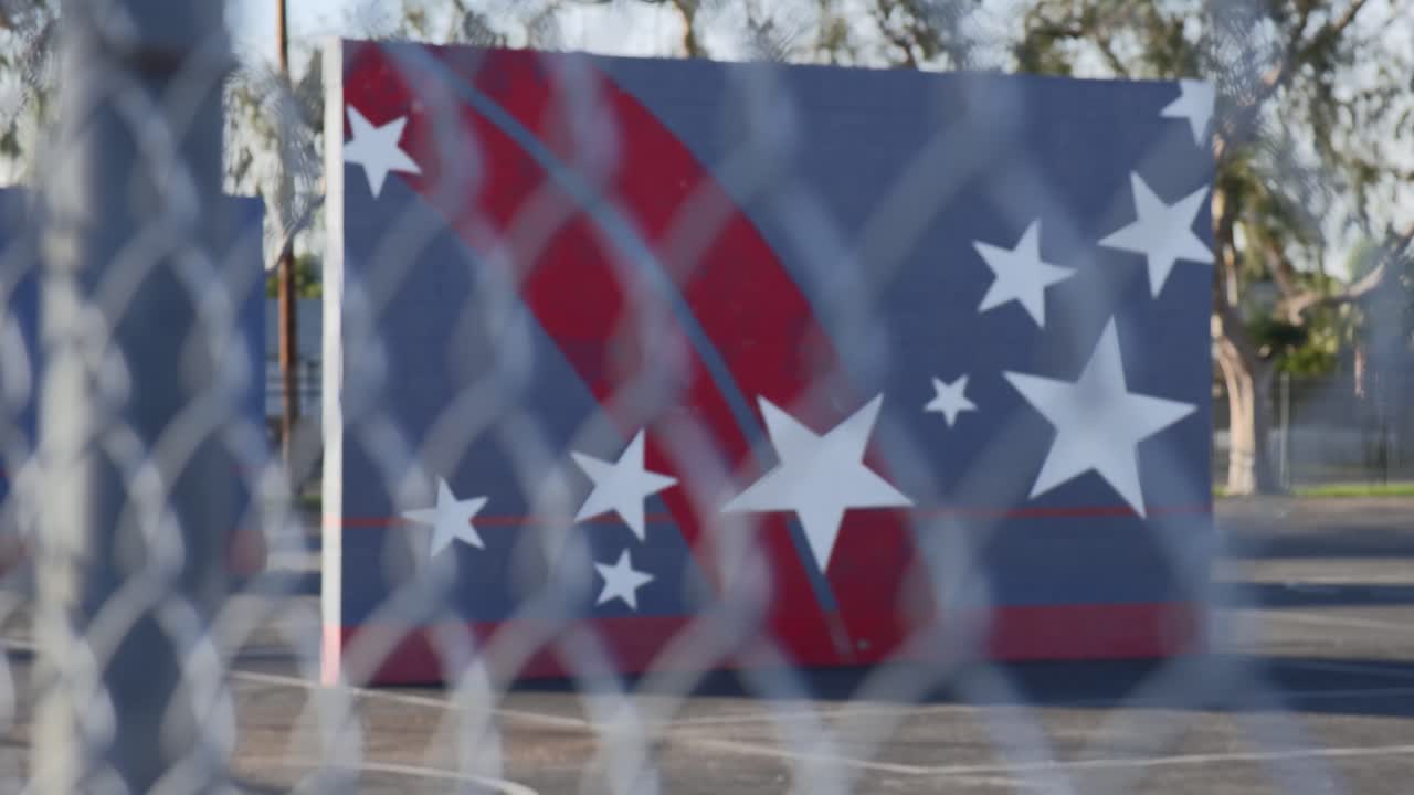 화창한 날 체인링크 울타리를 통해 빈 학교 운동장에 초점을 맞춥니다.