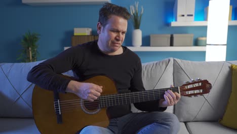 hombre infeliz y deprimido tocando su guitarra solo en casa.