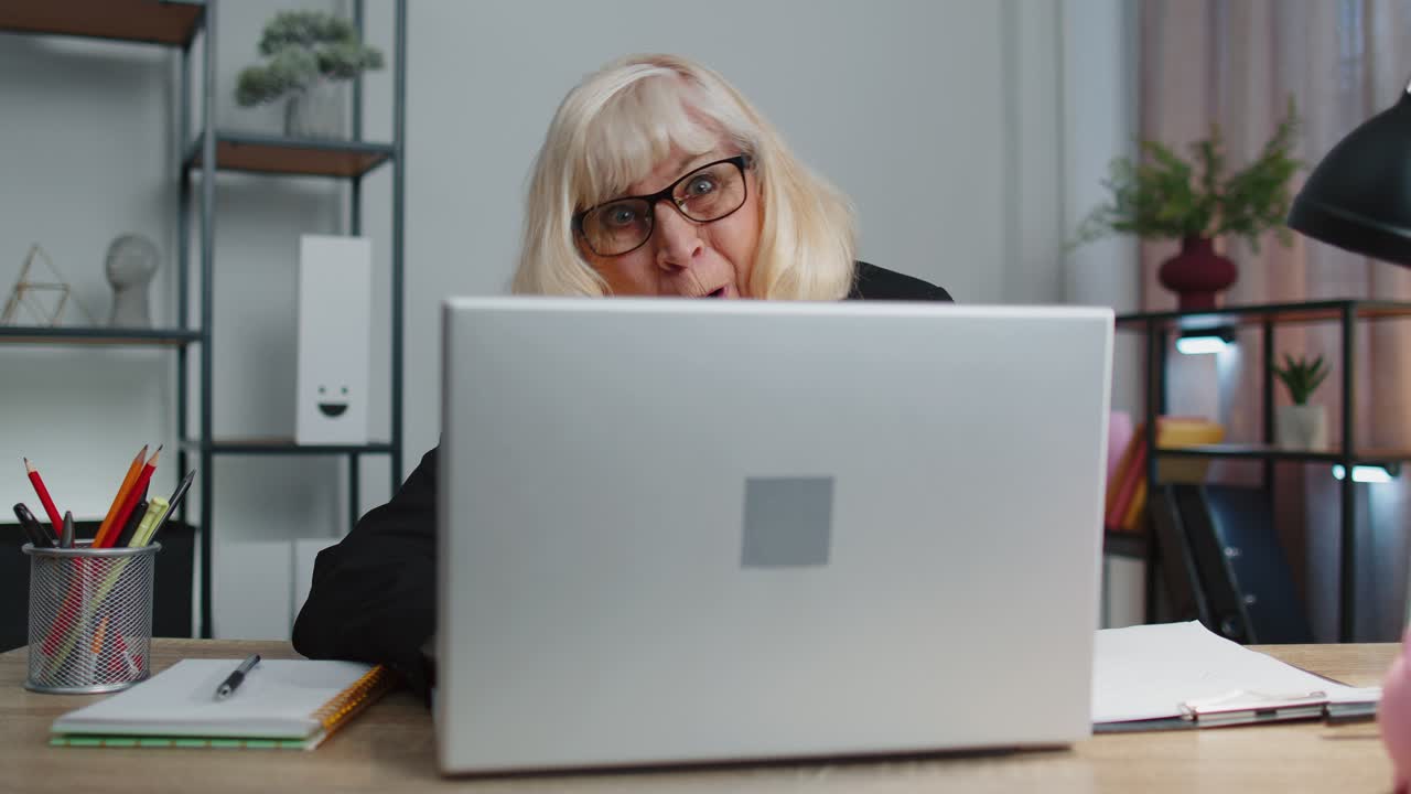 Senior mature older business woman hiding behind laptop computer making funny face fooling around