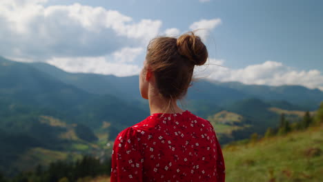 woman looking mountains scenery close up. back view of girl standing green hill.