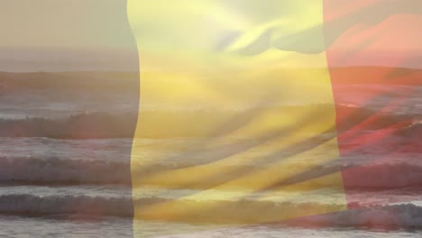 composición digital de ondear la bandera belga contra la vista de la playa y las olas del mar