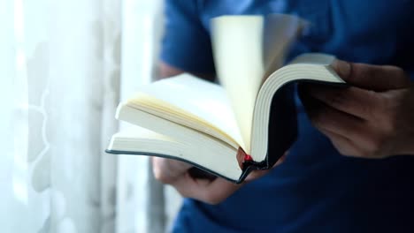 person reading an open book by a window