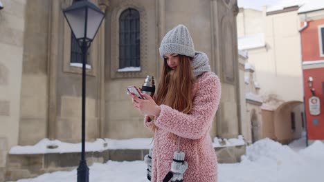 traveler woman holding mobile phone, chatting with friends and family, drinking hot drink tea