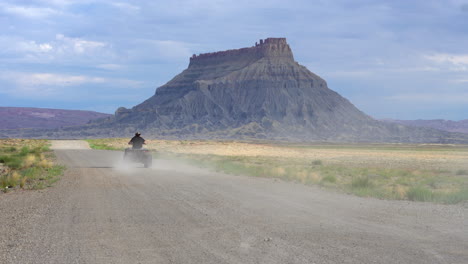 man skids and slides riding a quad bike on a dirt track at factory butte, hanksville utah, usa