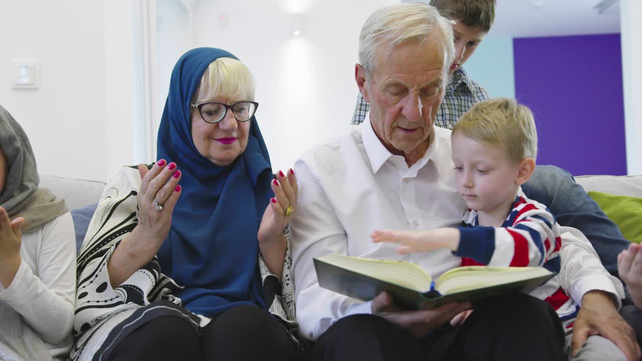 무슬림 가족 세대 할아버지와 할머니가 집에서 손자들과 함께 꾸란을 읽고 있습니다.