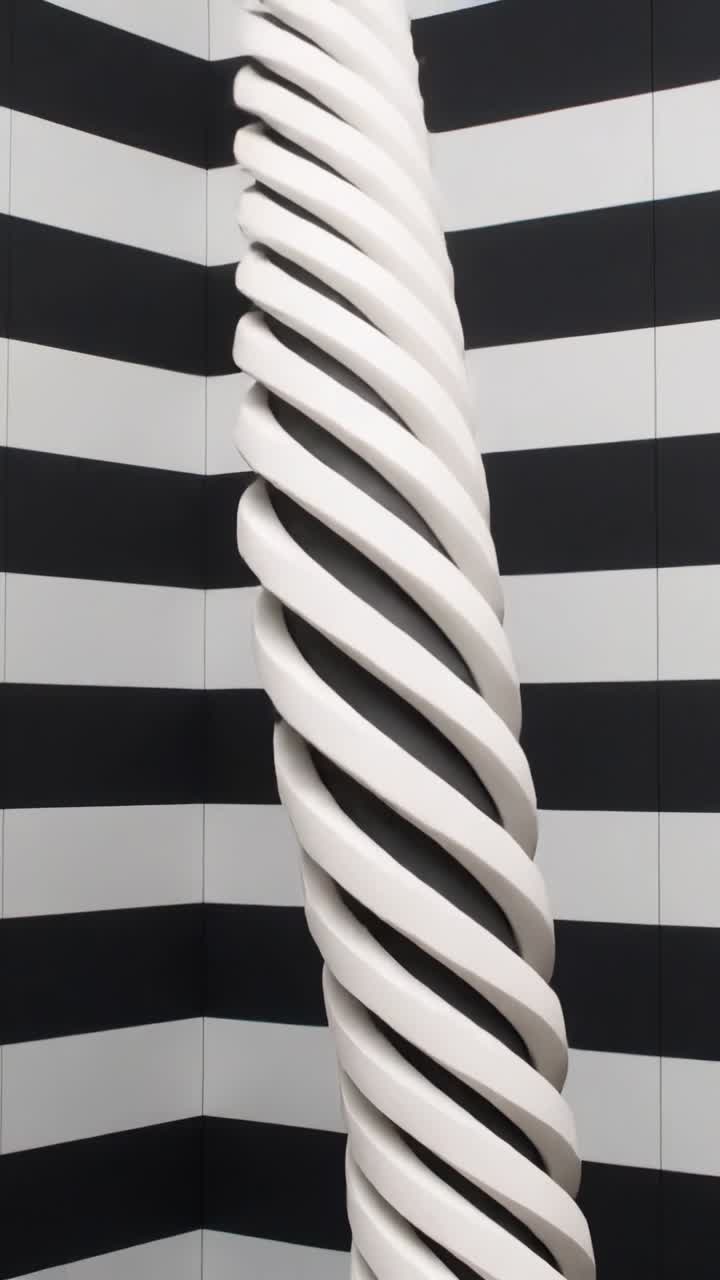 Video verticale: La telecamera si allontana rivelando una colonna a spirale bianca in un angolo a strisce, con la polvere che cade