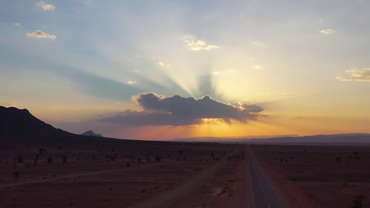 Aerial panorama shot of beautiful sunset with sunbeams behind cloud over dried Sahara Desert in africa
