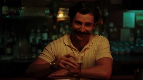 man with a mustache enjoying a beer at a bar
