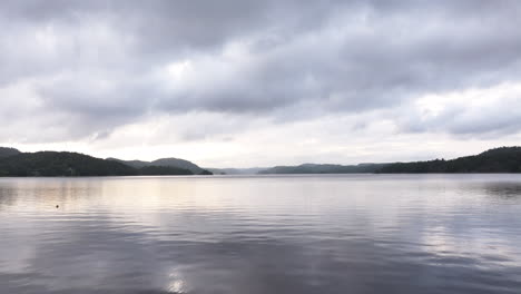 flying over farris lake on a cloudy day in norway - aerial drone shot