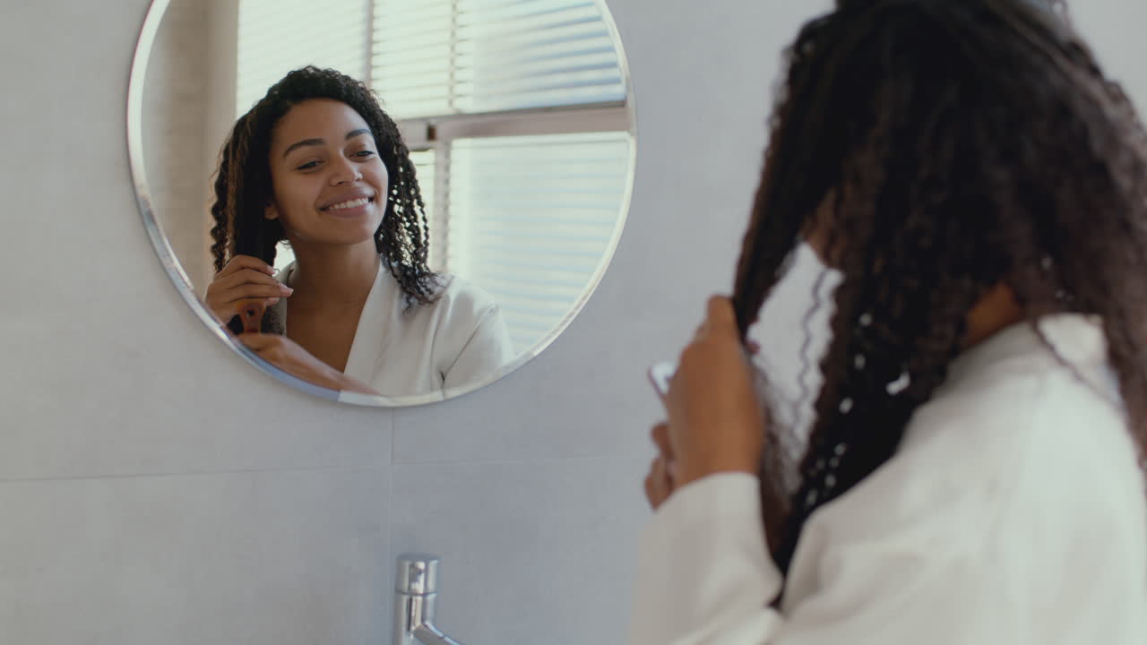 Donna che si pettina i capelli ricci in bagno