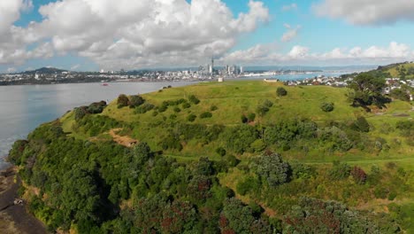 Toma-Aérea-De-La-Cabeza-Norte-Con-El-Horizonte-De-Auckland-En-El-Fondo,-Nueva-Zelanda