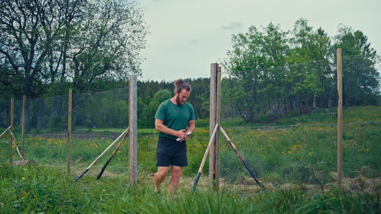 Man Building Fence With Metal Wire Mesh - Wide Shot