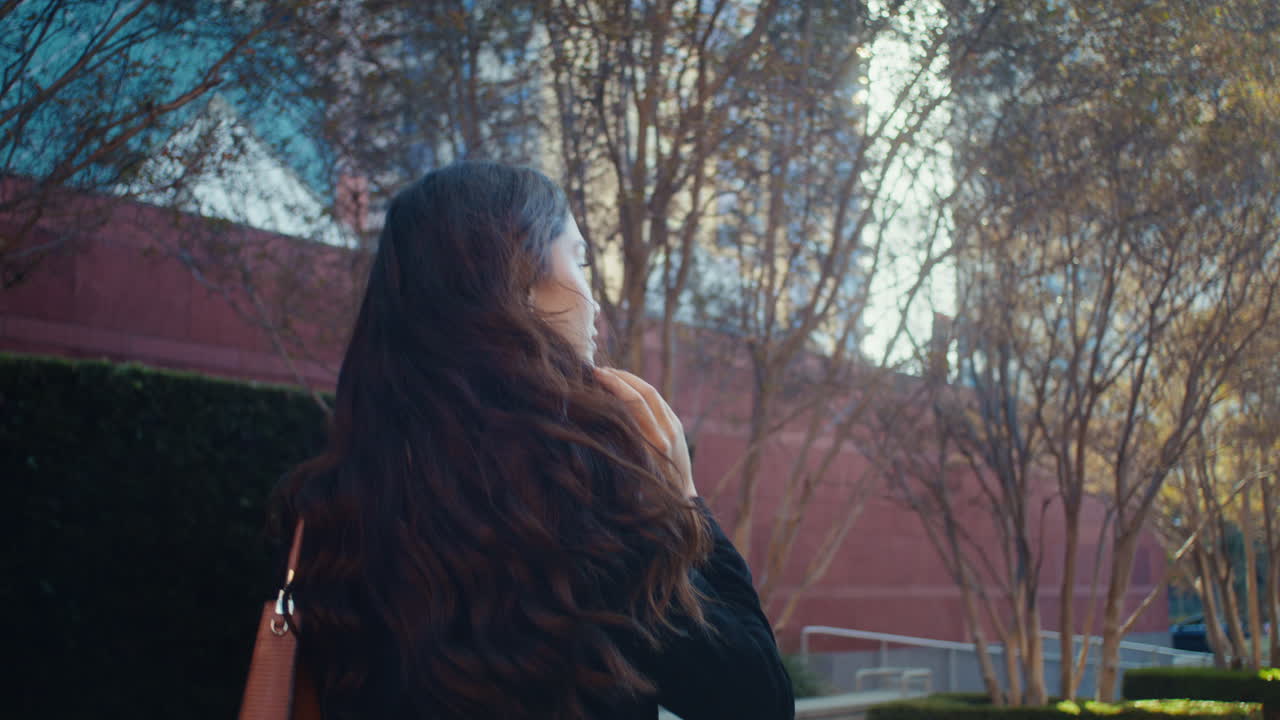 갈색 여자가 돌아서서 걸어가는 메가폴리스, 빛에 있는 아시아 소녀, 뒷면