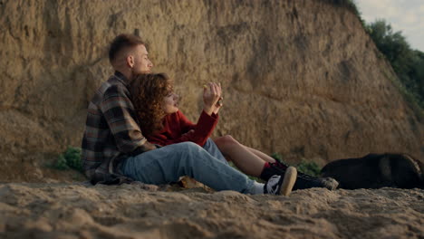 young couple dating on sunset sea beach. lovers checking photos on smartphone