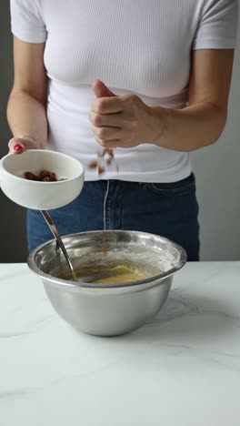 woman mixing raisins into cake batter