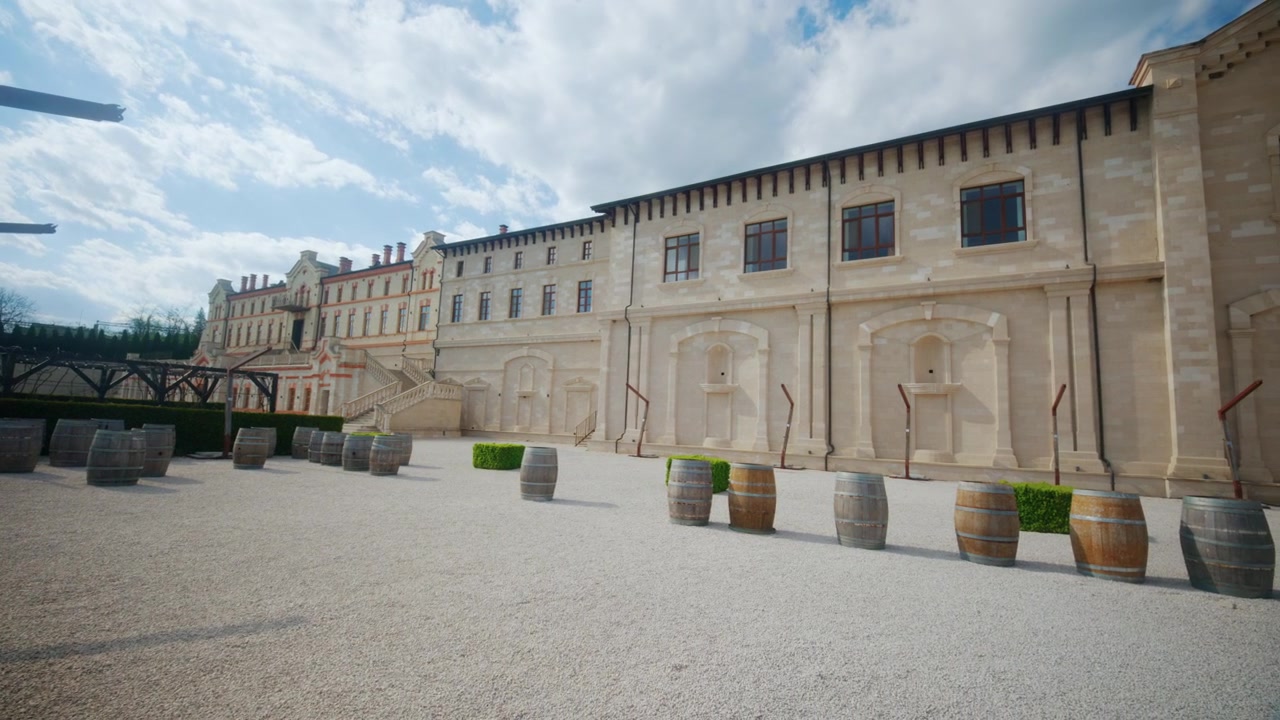 Ampia vista del cortile di un castello vinicolo in Moldavia, che mostra storici edifici vinicoli, facciate in pietra, botti di vino, sentieri di ghiaia e scalinate architettoniche