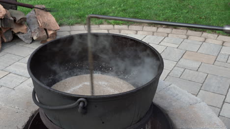 mixing ground meat or puttons in an iron kettle over a wood fire