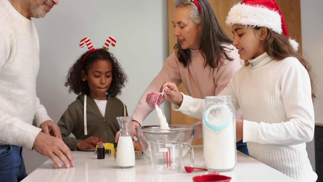 Diverse family gathering around kitchen island preparing holiday batter after father placing eggs