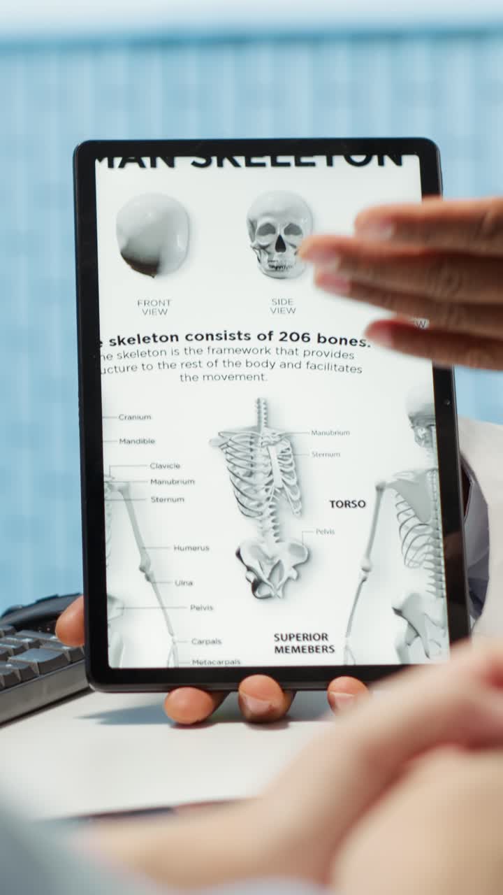 Læge forklarer menneskeskeletdiagram på tablet til patienten.