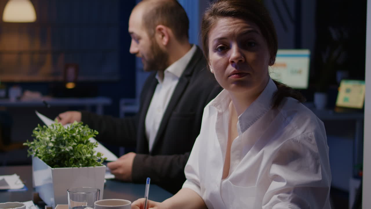 Portrait of smiling businesswoman looking into camera working overtime in business company meeting office