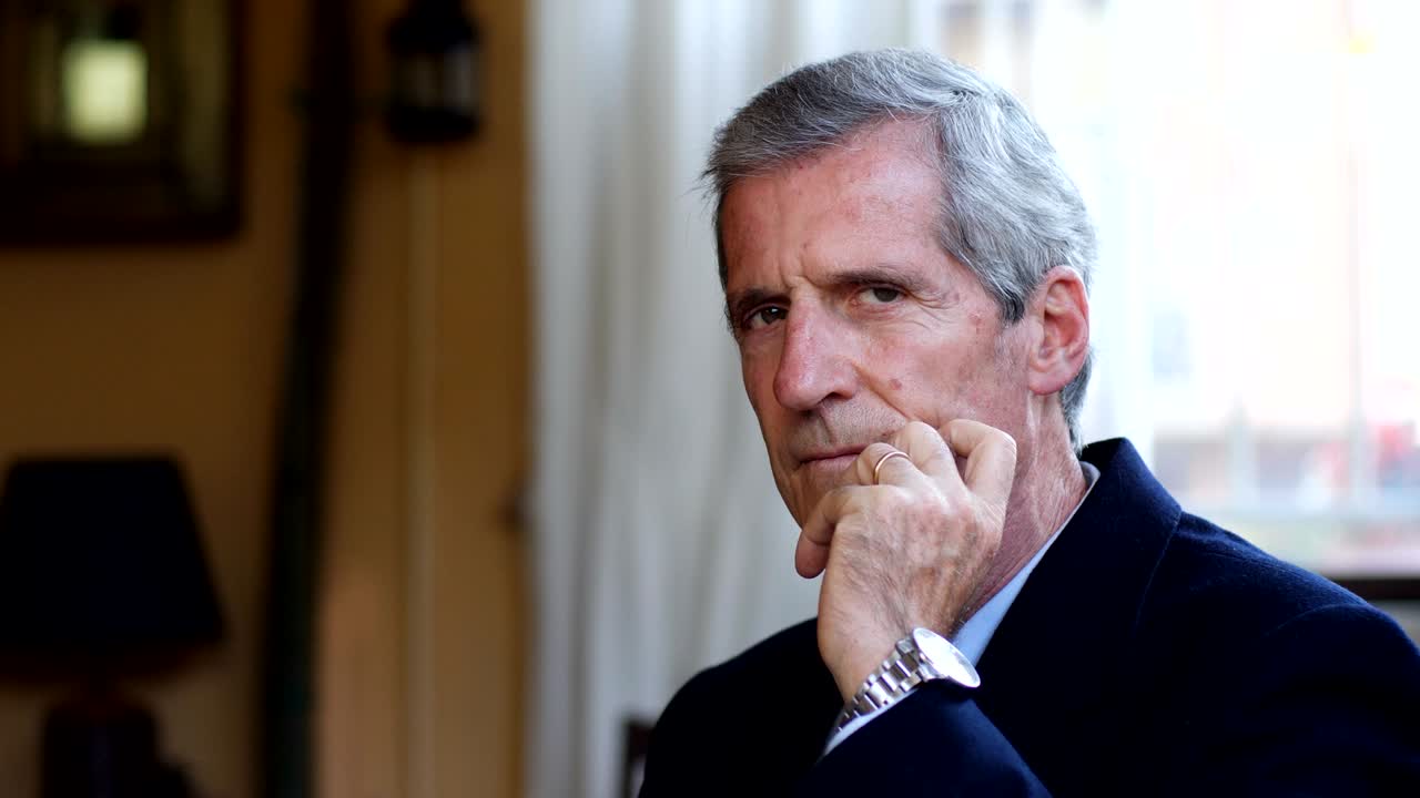 el viejo gerente confiado en su oficina mirando a la cámara