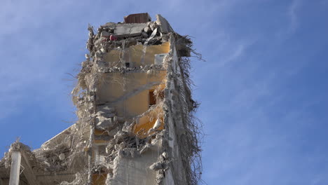 demolished building against blue sky, concrete and steel swaying in the wind