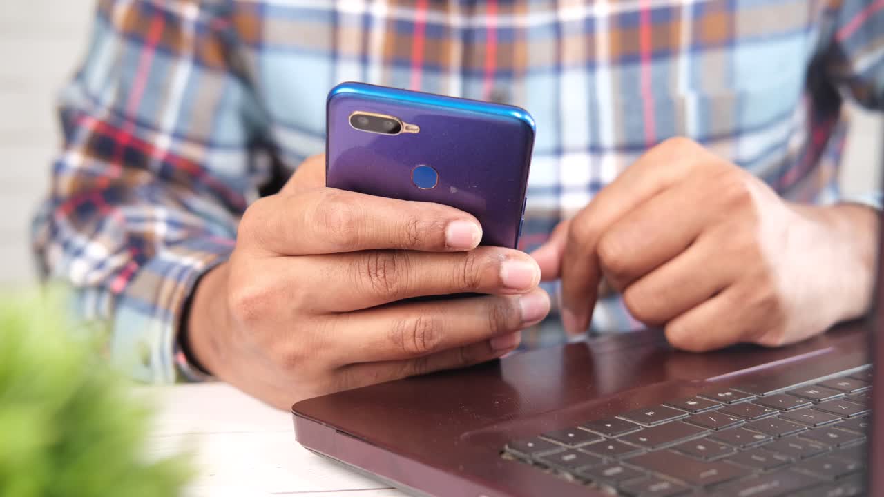 persona que utiliza un teléfono inteligente y una computadora portátil