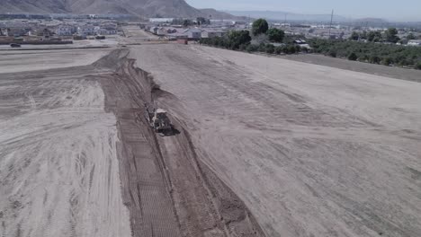 A-drone-observes-a-track-loader-efficiently-moving-earth,-skillfully-preparing-the-ground-for-the-start-of-a-new-home-construction-site