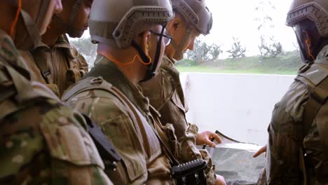 Side-view-of-mixed-race-military-soldiers-with-rifle-planning-during-military-training-4k