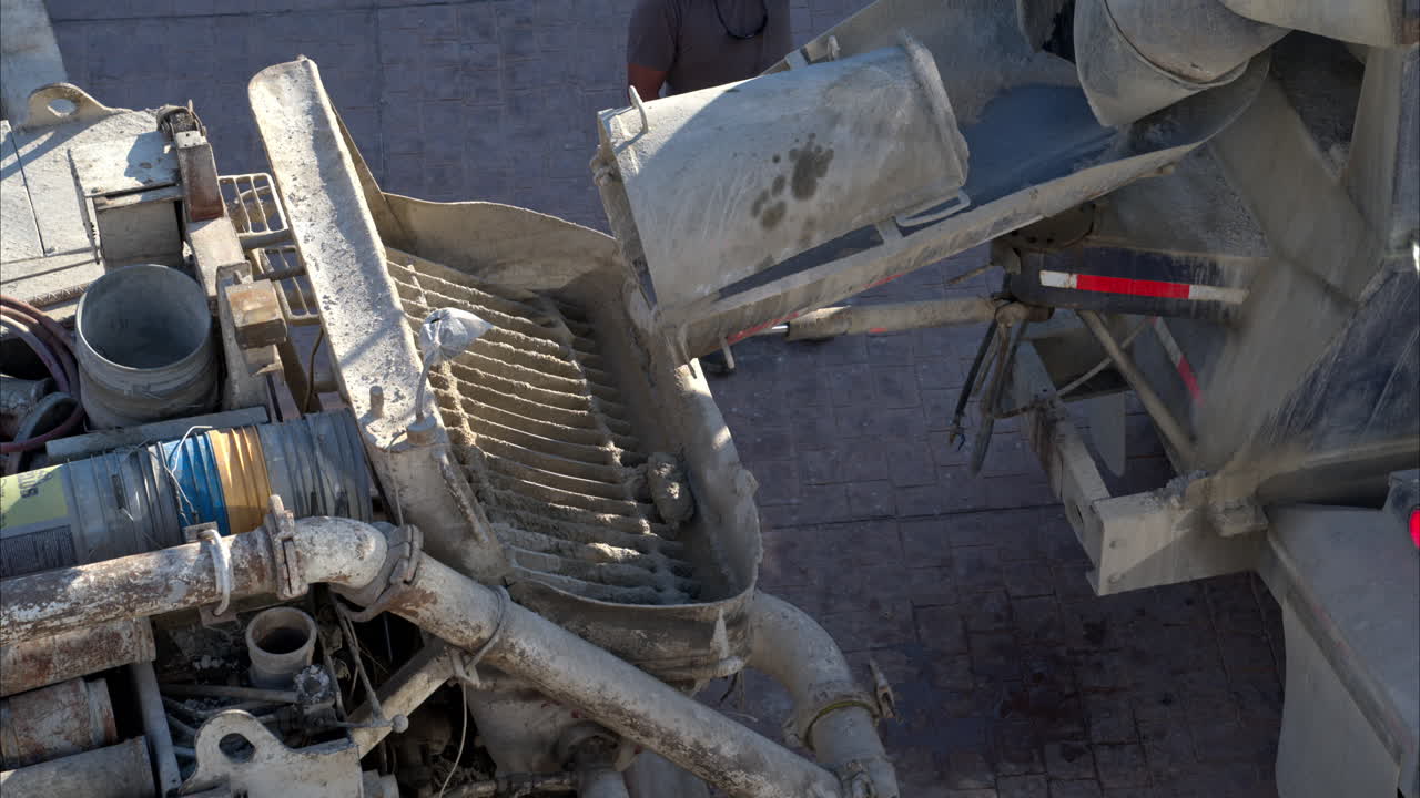 Slow motion of a concrete mixer truck driving in reverse aligning with the back of a boom pump truck